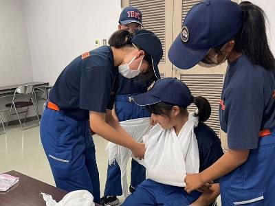 三角巾を使った応急手当の練習をする少年消防団員たち