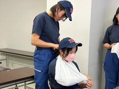 三角巾を使った固定法を学ぶ少年消防団員
