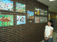 市庁舎の壁面に展示されている児童が描いた絵画を女性が見ている写真