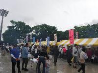 のぼり旗を立てた出店が並んでおり、お客さんがお店の前に並んで賑わっている様子の写真