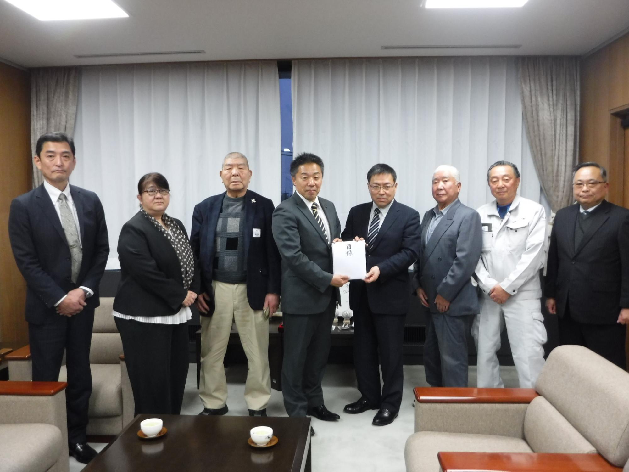 大和市全国県人会連合会事務局長などを含めた7名が古谷田市長に義援金を手渡ししている写真