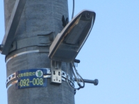 電信柱に防犯灯管理プレートと防犯灯が設置されている写真