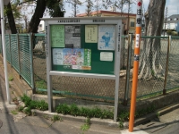 緑のフェンスの前の掲示板に案内が貼られている写真