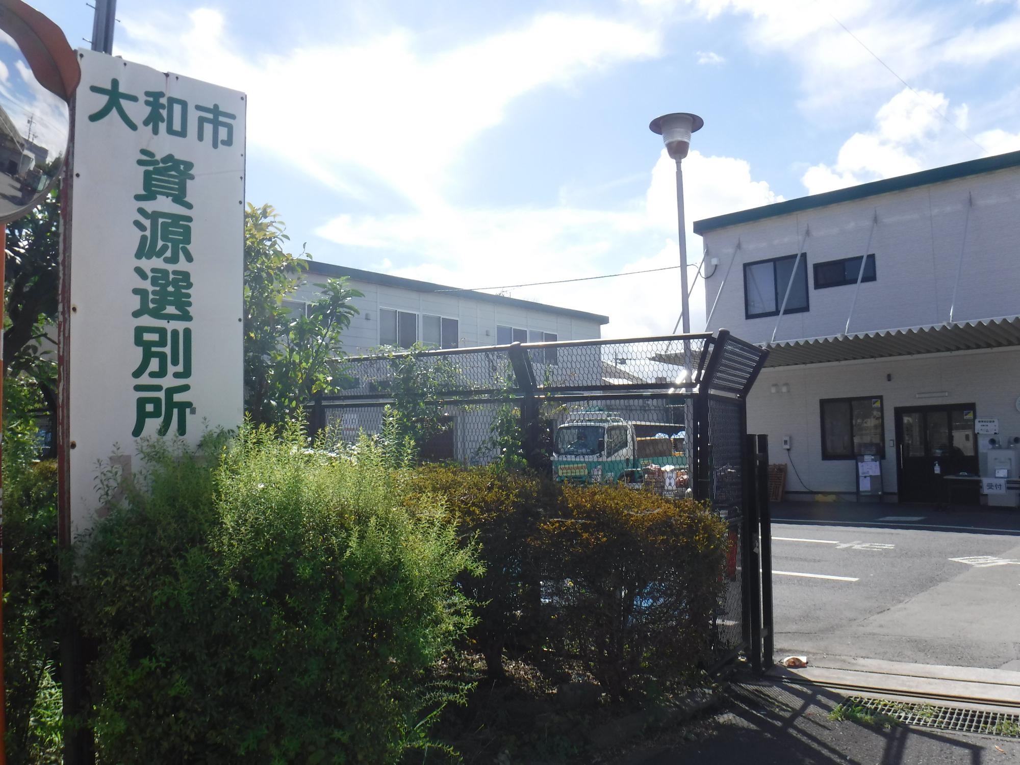 左側に「大和市資源選別所」と書かれた看板があり、奥にプレハブの建物などが見える大和市資源選別所の写真