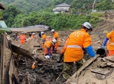 オレンジの消防服を着た団員たちが土石流の中、瓦礫をかき分けながら捜索作業を行っている写真