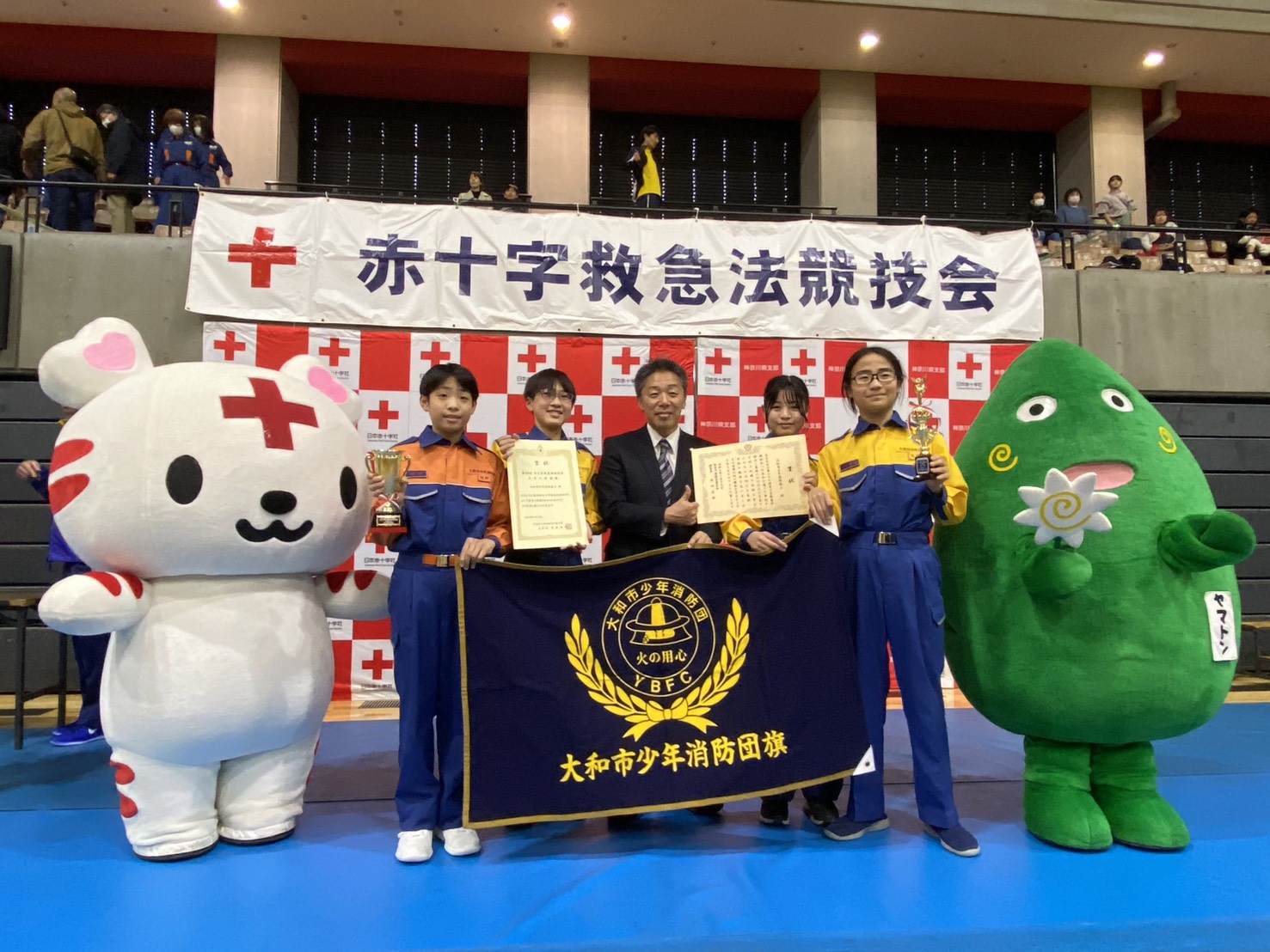 大和市少年消防団が賞状やトロフィー、旗を持って、市長と記念撮影をしている様子