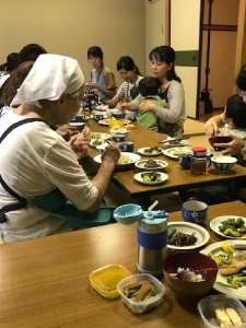 机に並べられた食事を試食している参加者の人達の写真