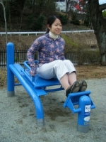 女性がカーフベンチに座り、足を曲げた状態で前方にある板に両足をかけている写真