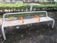 外側が白いパイプのベンチの真ん中に2つオレンジ色の持ち手が付いているあしこしベンチの写真