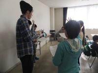 帽子を被った講師に児童たちが手を挙げて質問をしている写真
