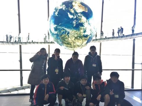 日本科学未来館の地球の模型がある場所で記念写真を行っている参加者たちの写真