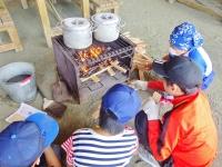 野外炊事場でカレーを作っている子供4人の写真