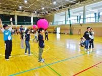 体育館の中でピンクのボールを持ちレクレーション活動をしている子供たちの写真
