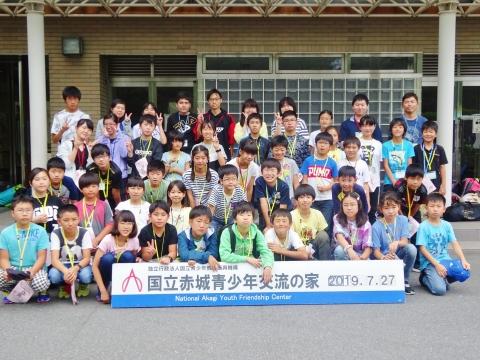 国立赤城青少年交流の家の前で記念写真を撮る夏の宿泊研修に参加した子供達の写真