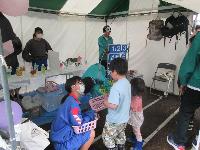 テント下の子ども向けゲームコーナーを楽しむ子どもと運営するボランティアの写真