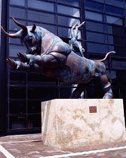大きな闘牛が後ろ脚で立ち、牛の背中に両手をついて逆上がりしている人を描いた石像の写真