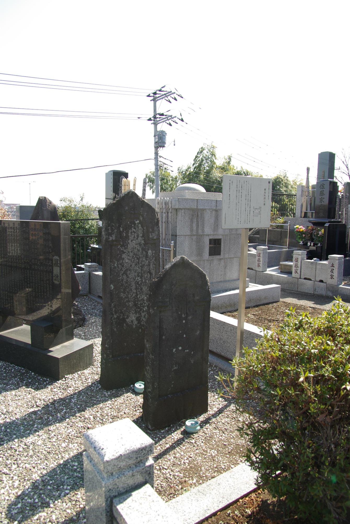 墓誌の横に板碑型の墓が2つ並びその前に線香立てが置かれている写真