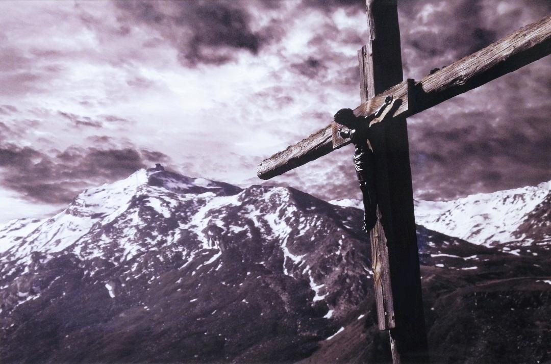 薄暗い空の下、雪山と手前には十字架が写っている写真