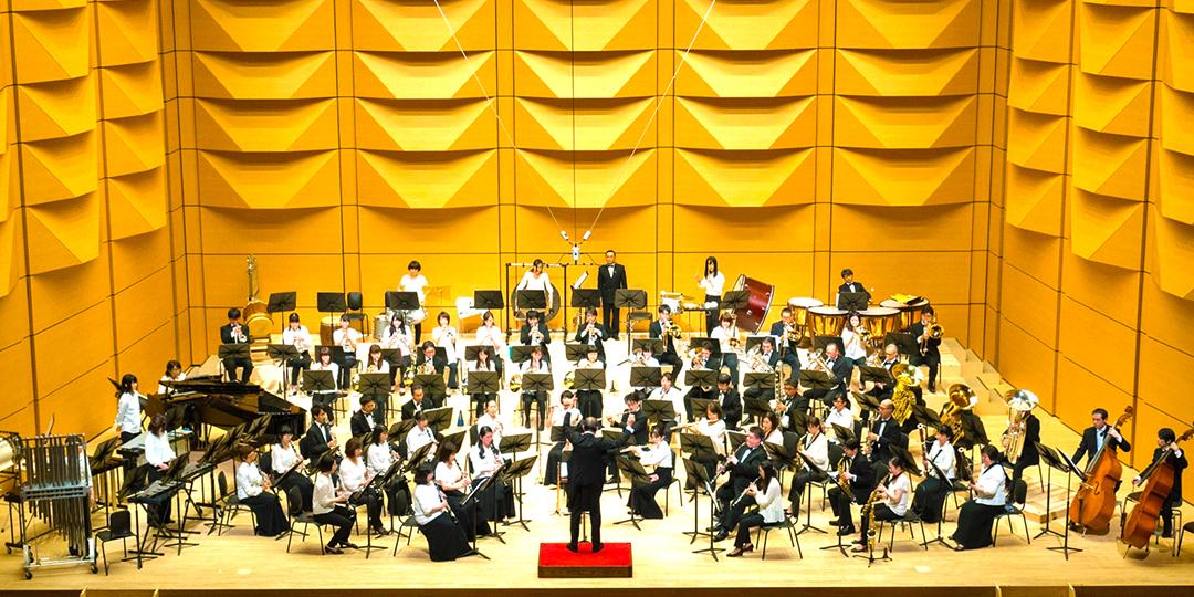 舞台で指揮者を前に、大和市民吹奏楽団の方々が演奏する写真