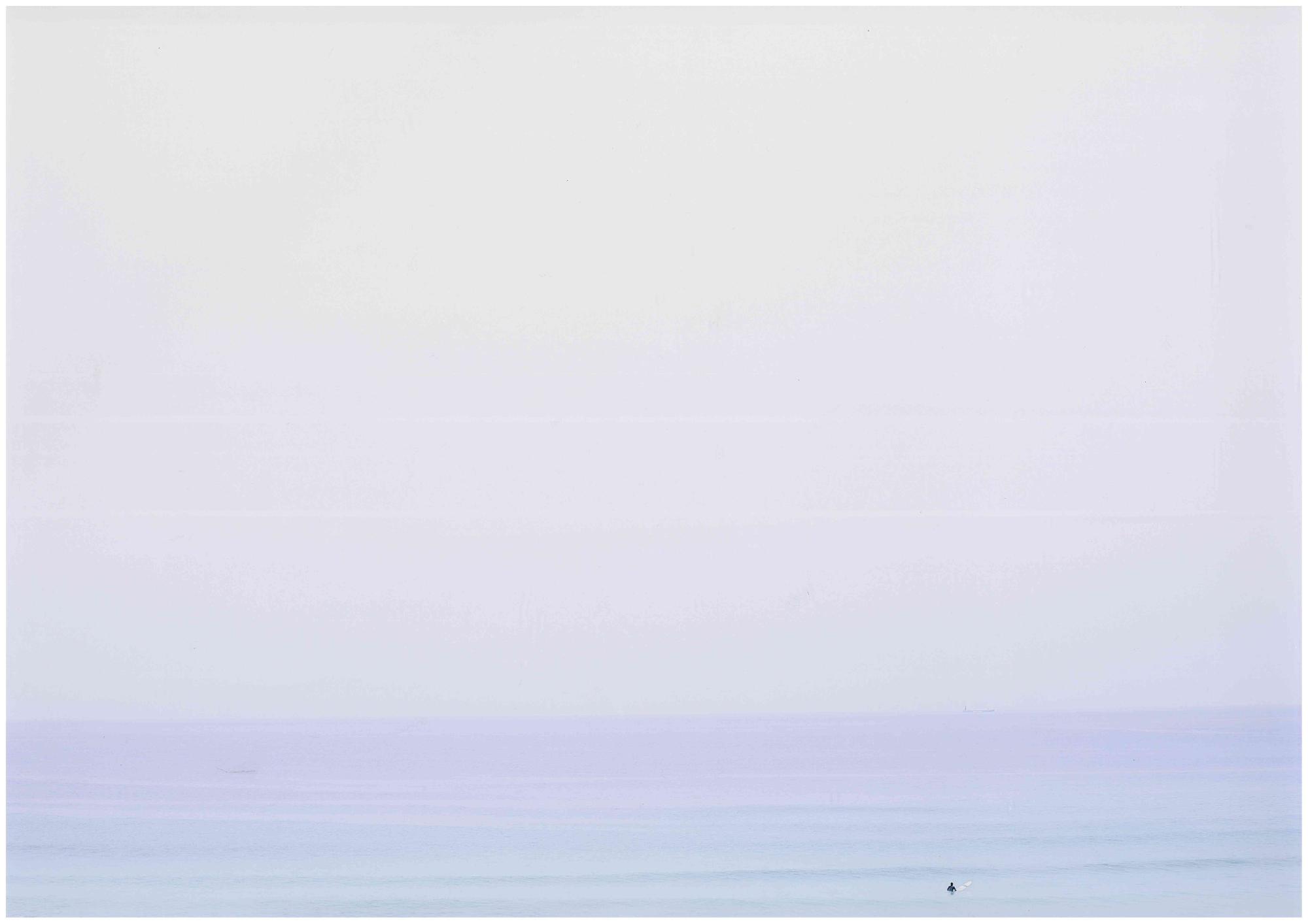 青い海が一面に広がり、サーファー1名が写っている写真