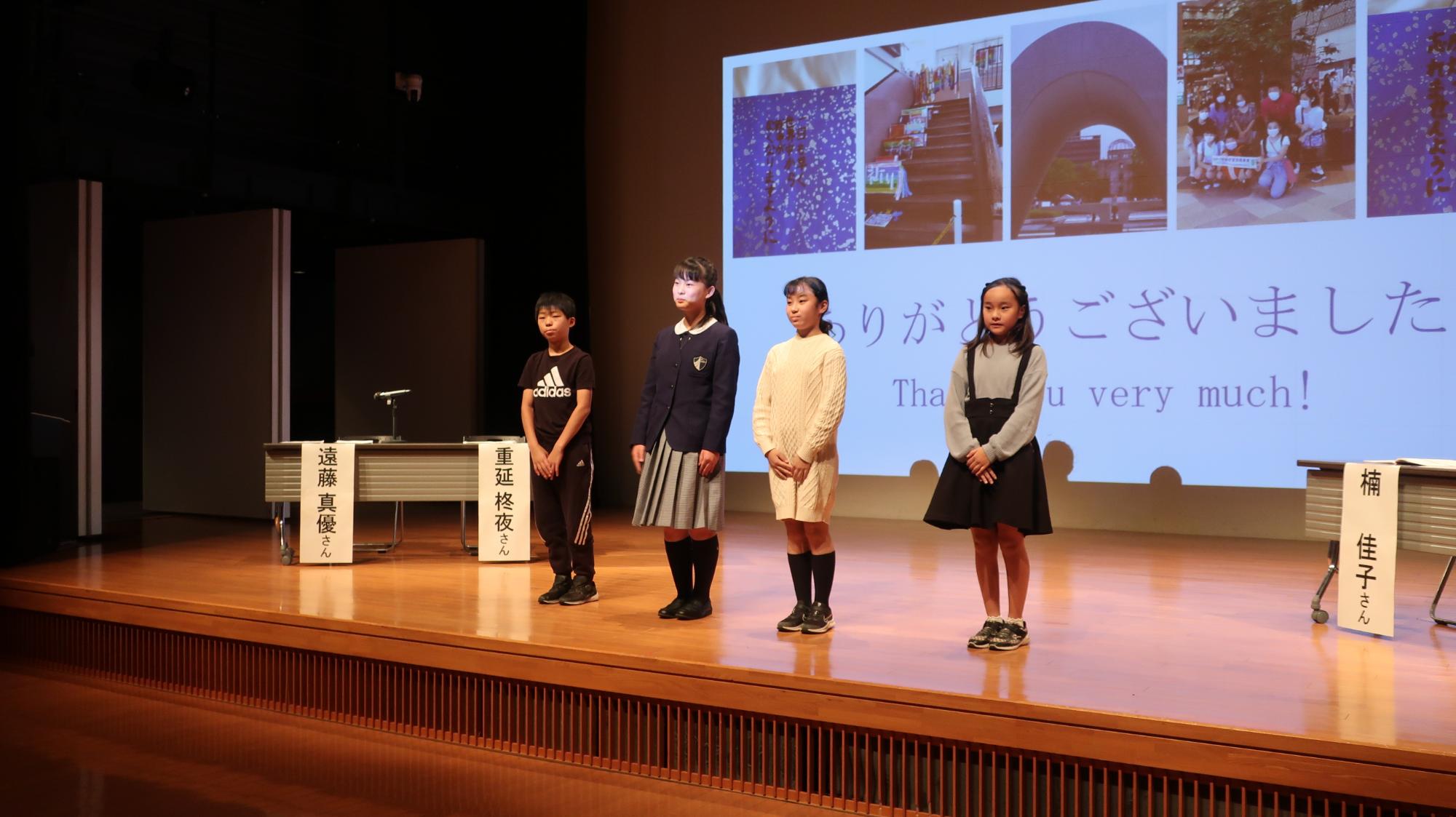 広島平和学習報告会発表後の挨拶の様子。壇上で4人の児童が横並びになり挨拶をしている様子。