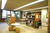 本が沢山詰まった本棚と、丸テーブルと椅子が設置されている学習センター図書室内の写真