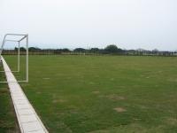 広い芝生の白線の上のゴールポストを横から写した写真