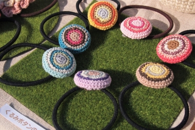 毛糸を編んでカラフルな模様がついたくるみボタンのゴムが7個並べてある写真
