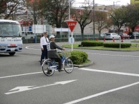 交通安全自転車大会で、路上で一時停止している自転車とそれを確認している男性の写真