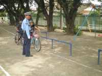 警察の方が公園で自転車に乗る児童に乗り方を教えている様子の写真