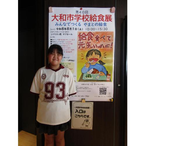 ポスターに採用された児童が給食展に来場し、自分のポスターと記念写真