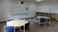 4脚の椅子が置かれた丸いテーブルが2組ある通級指導教室「はぐくみの教室」の室内写真