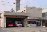 車庫に消防車両と救急車両が駐車されている白い外観の大和市消防署西出張所庁舎の写真