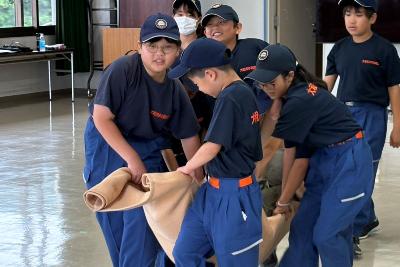 毛布担架で傷病者搬送訓練をする少年消防団員