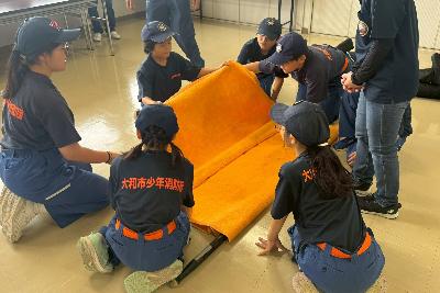 毛布担架で傷病者搬送訓練をする少年消防団員