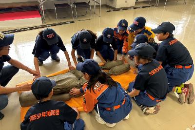 毛布担架で傷病者搬送訓練をする少年消防団員