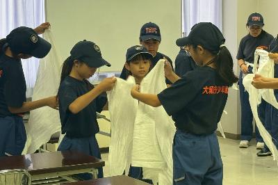 毛布担架で傷病者搬送訓練をする少年消防団員