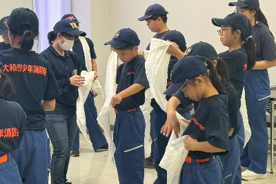 毛布担架で傷病者搬送訓練をする少年消防団員