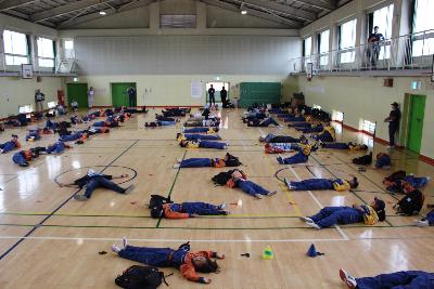 体育館で雑魚寝体験をする少年消防団員