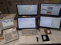 タッチパネルの機械や、キーボード、4台のスクリーンが置かれてある指令台の写真