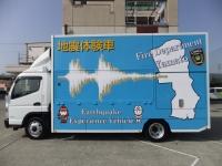 水色の車体に地震体験車と書かれたトラックを左側から撮影した写真